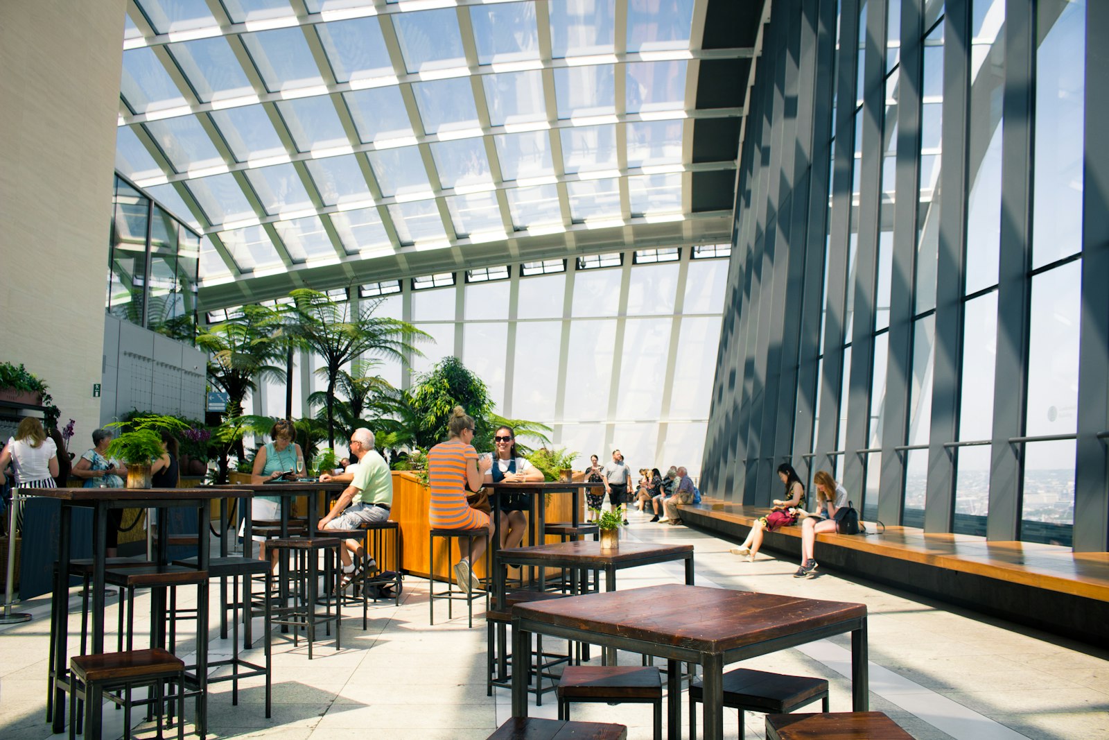 Visiteurs attablés au bar du Sky Garden, devant les baies vitrées